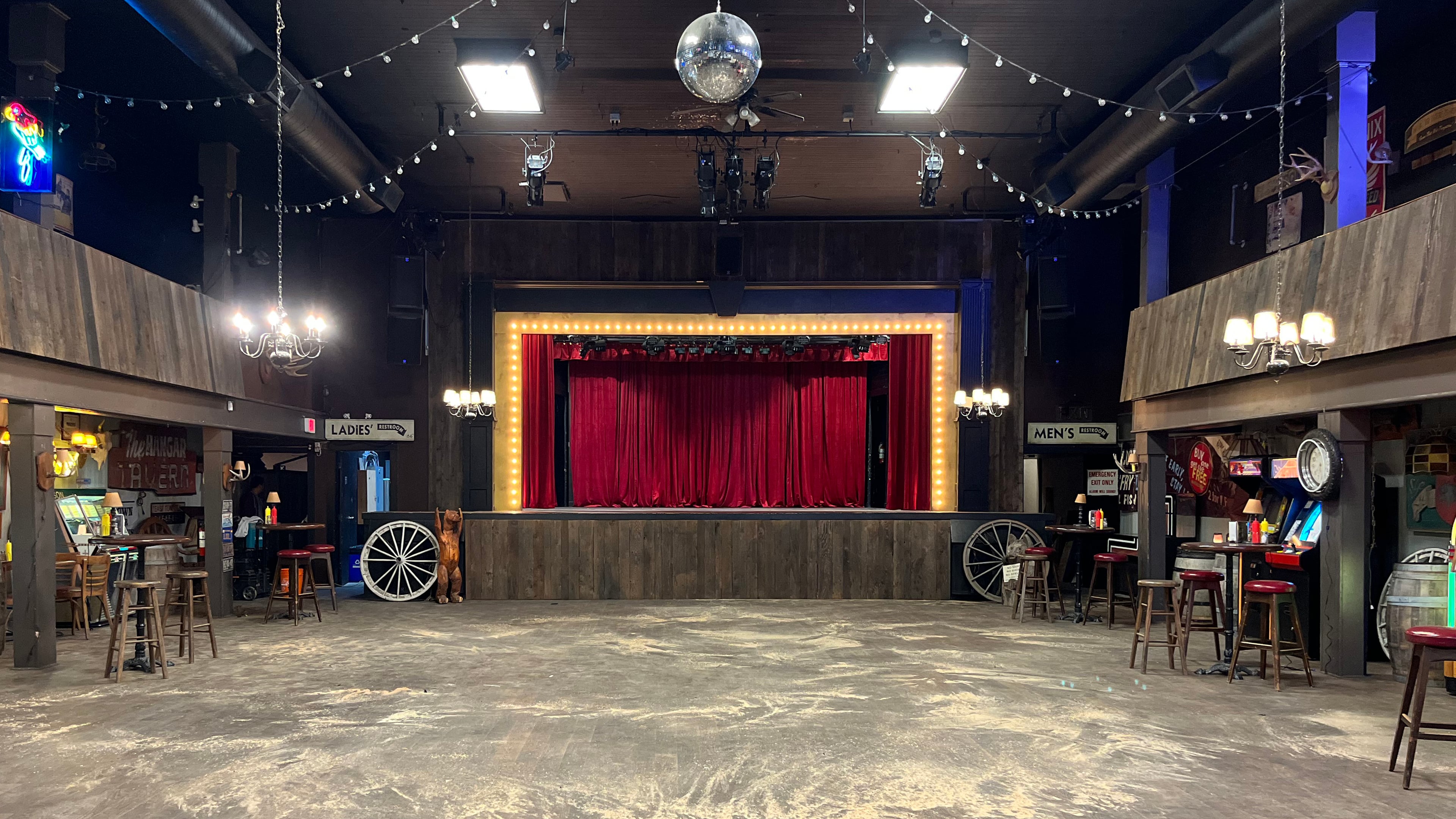 Western honkytonk bar set with red curtain stage, disco ball, wagon wheels, and string lights for Expedia commercial