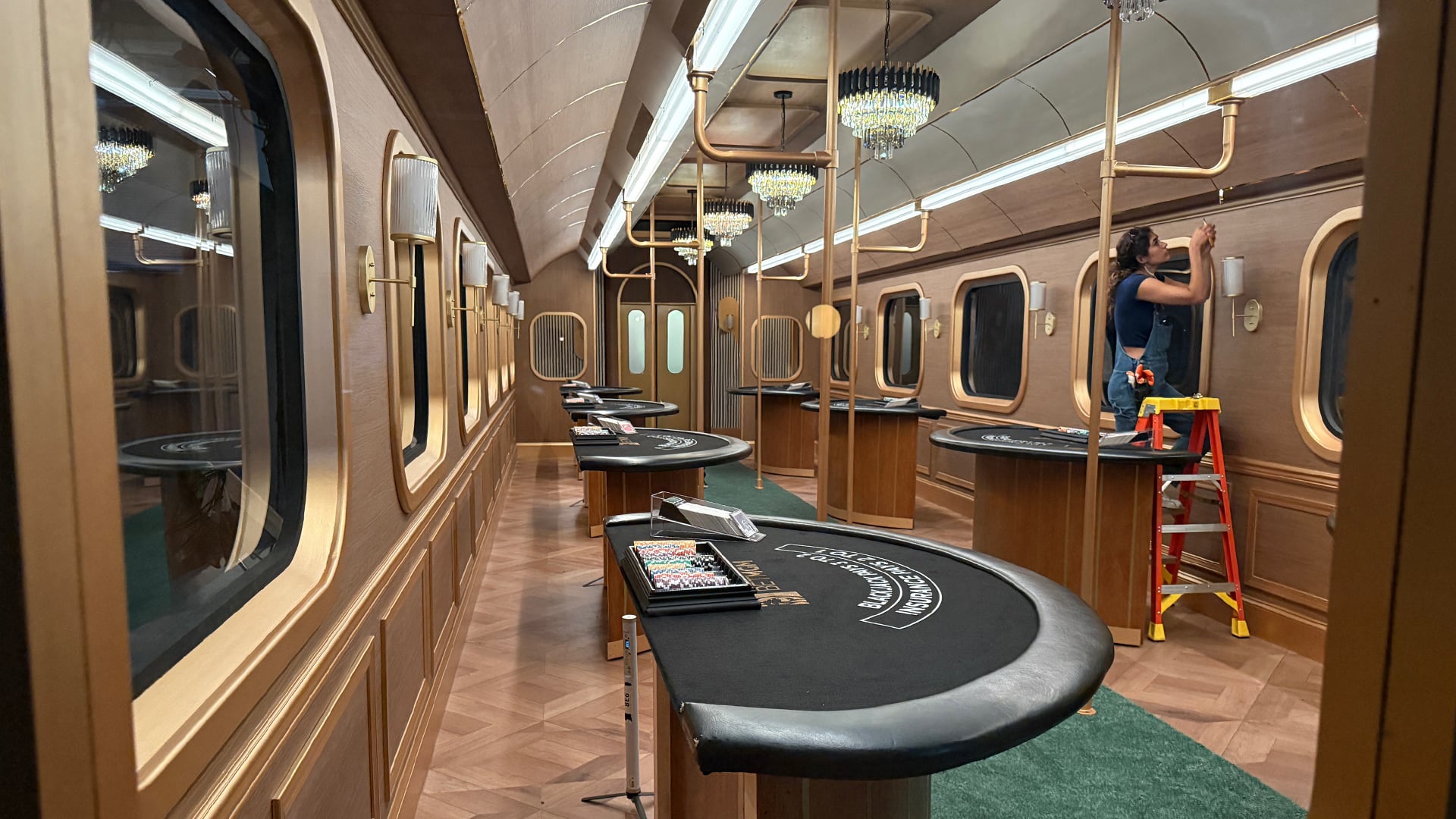 Luxury train casino car interior with blackjack tables, crystal chandeliers, and gold-trimmed windows for MGM Grand